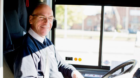 Närbild på medelålders man som sitter vid ratten i en buss.